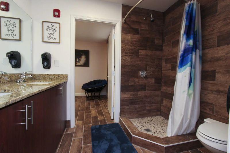 Inside bathroom that has double vanity, show stall, and toilet.